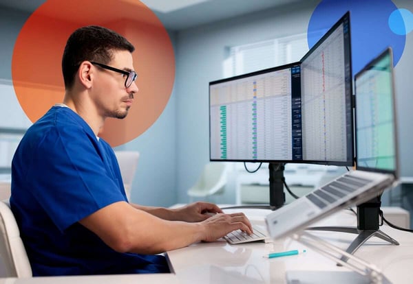 Clinician reviewing data across several monitors